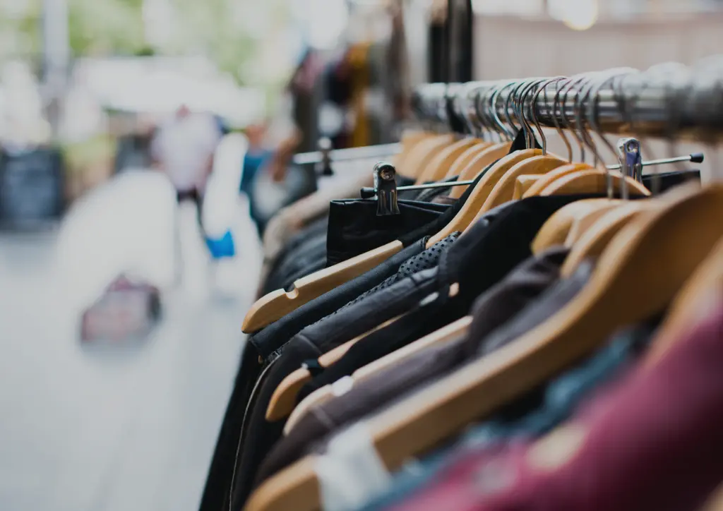 Wooden hangers with clothes on a clothing rack inside a retail shop